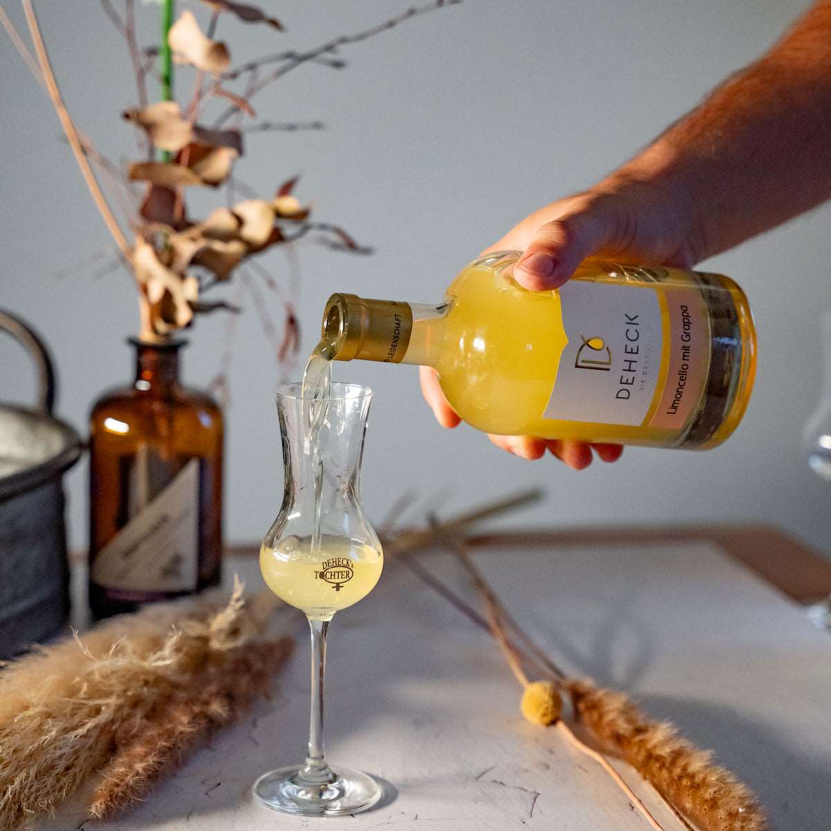Limoncello mit Grappa verfeinert wird in Likörglas eingeschenkt. Leckerer Likör von Deheck.
